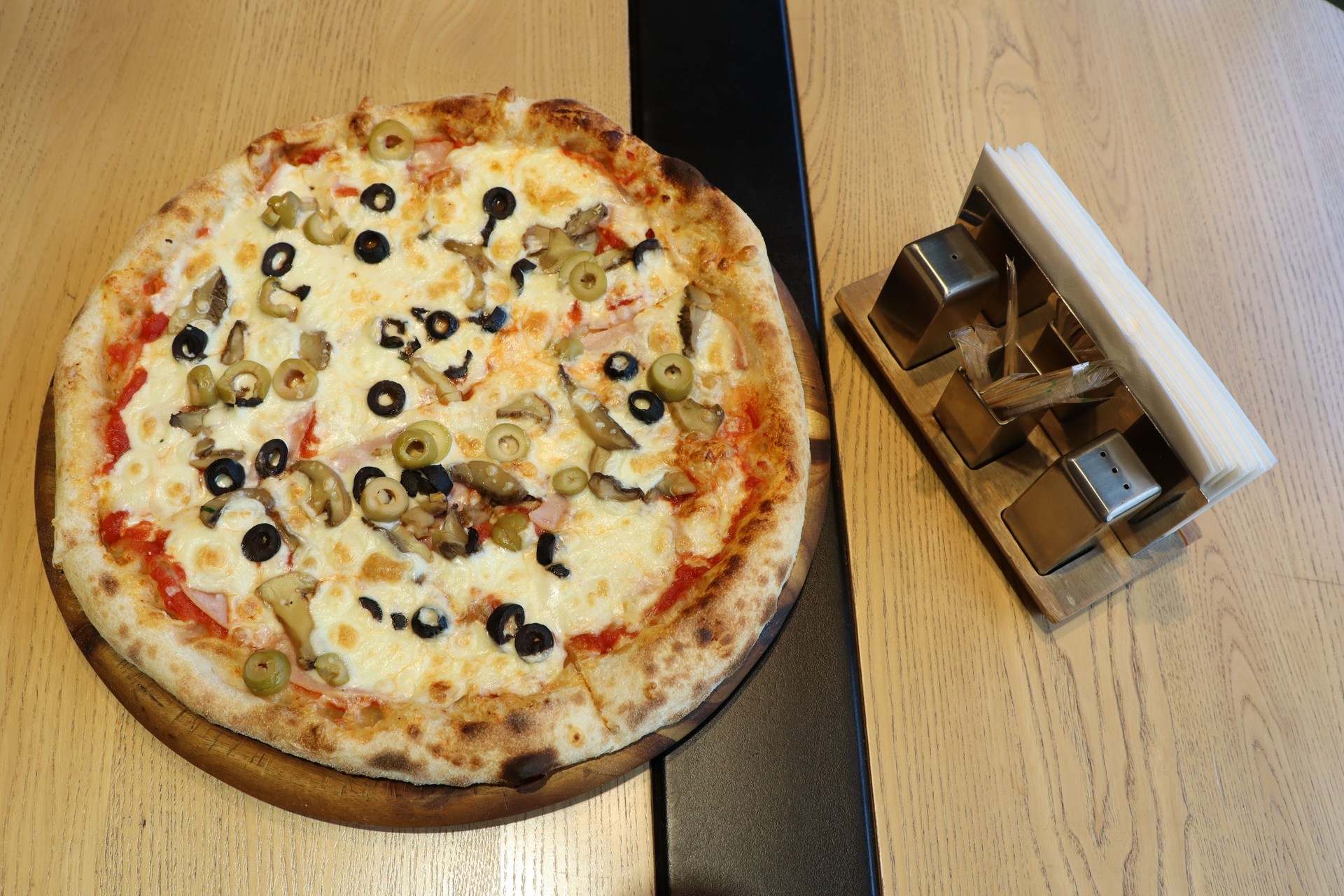 Enjoy a delicious pizza topped with a variety of ingredients, served on a rustic wooden board